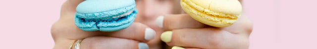 Colorful macarons held in hands.